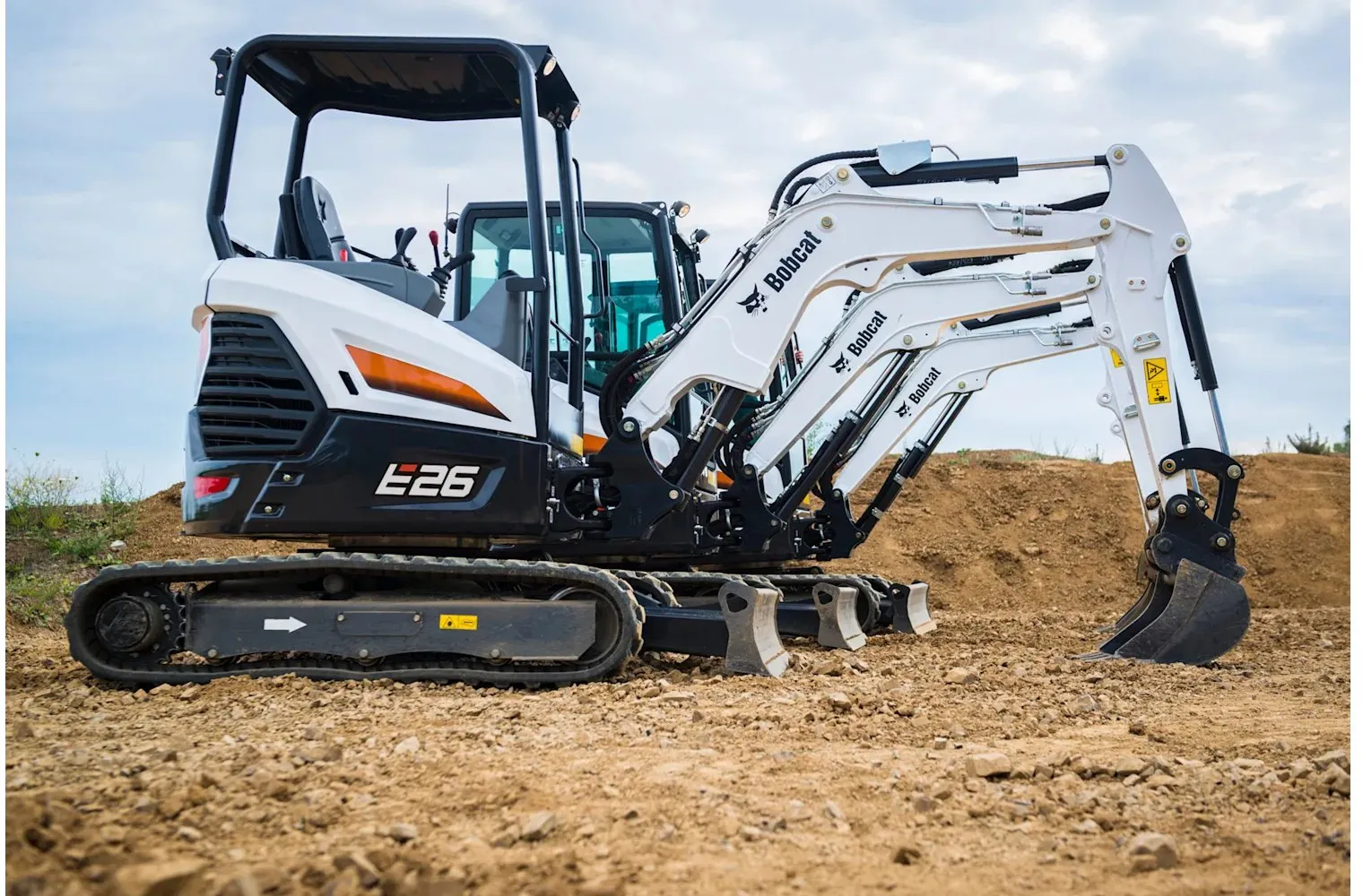 Bobcat E26 working a dirt pile, arm extended